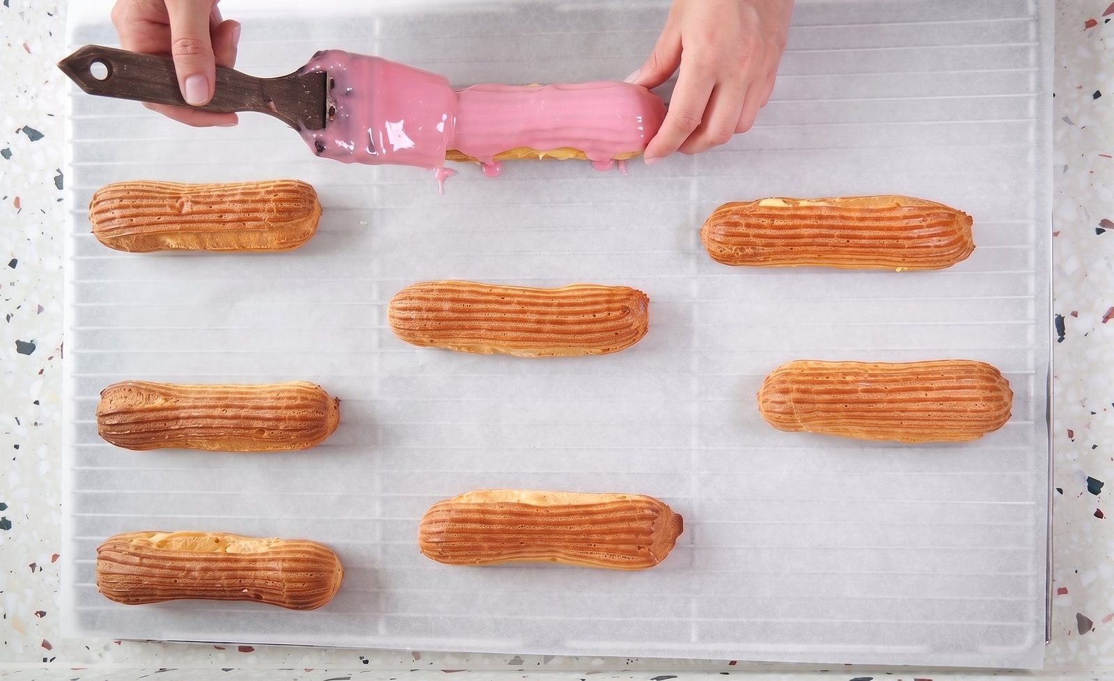 Eclairs werden von Hand mit rosa Fondant glasiert
